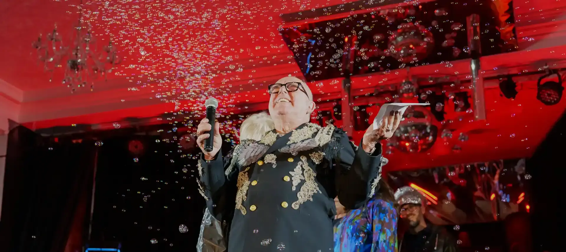 Host Darl Schaaff on stage as soap bubbles rain down to conclude the Wearable Art Fasion Show